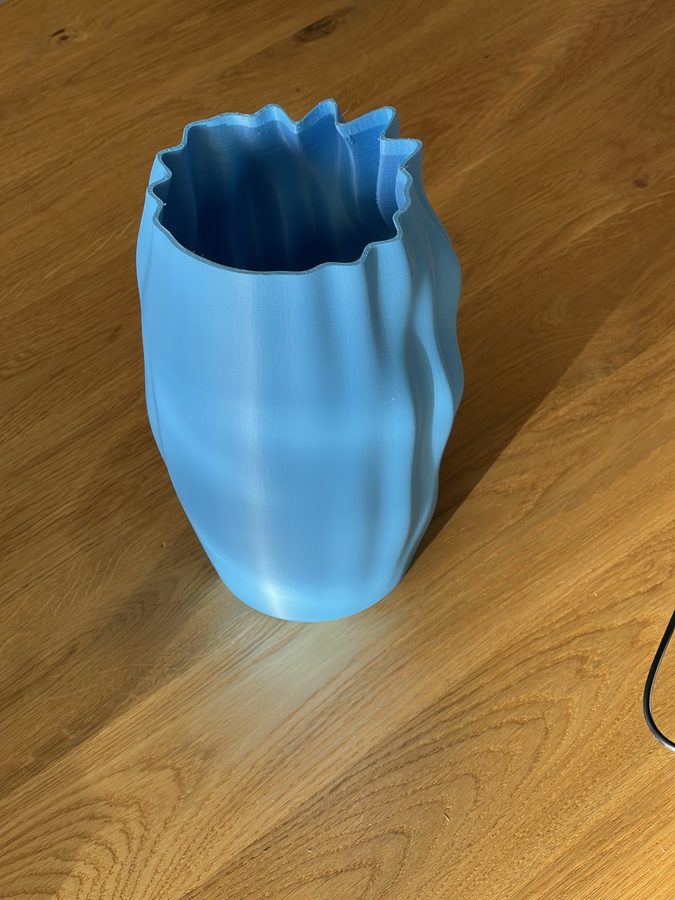 The printed sky-blue vase on an oak table, photographed on a phone